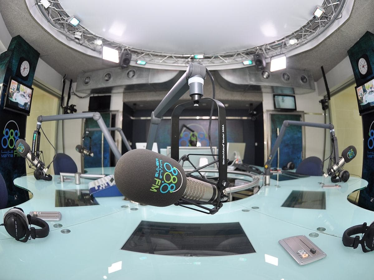 Photo: Shoulaqurashi (CC BY-SA 4.0), via Wikimedia Commons A professional radio studio with broadcast microphones